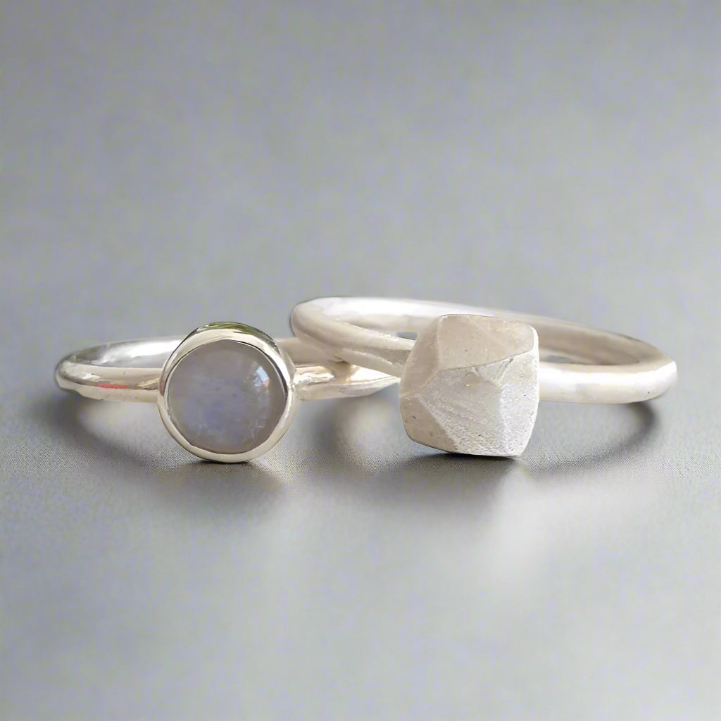 Two silver rings with moonstone on a textured surface
