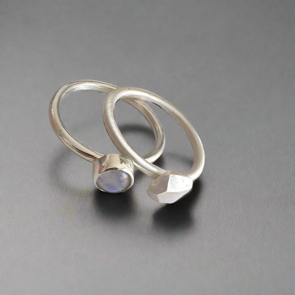 Two silver rings with gemstones on a light gray background