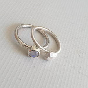 Two silver rings with gemstones on a light gray background